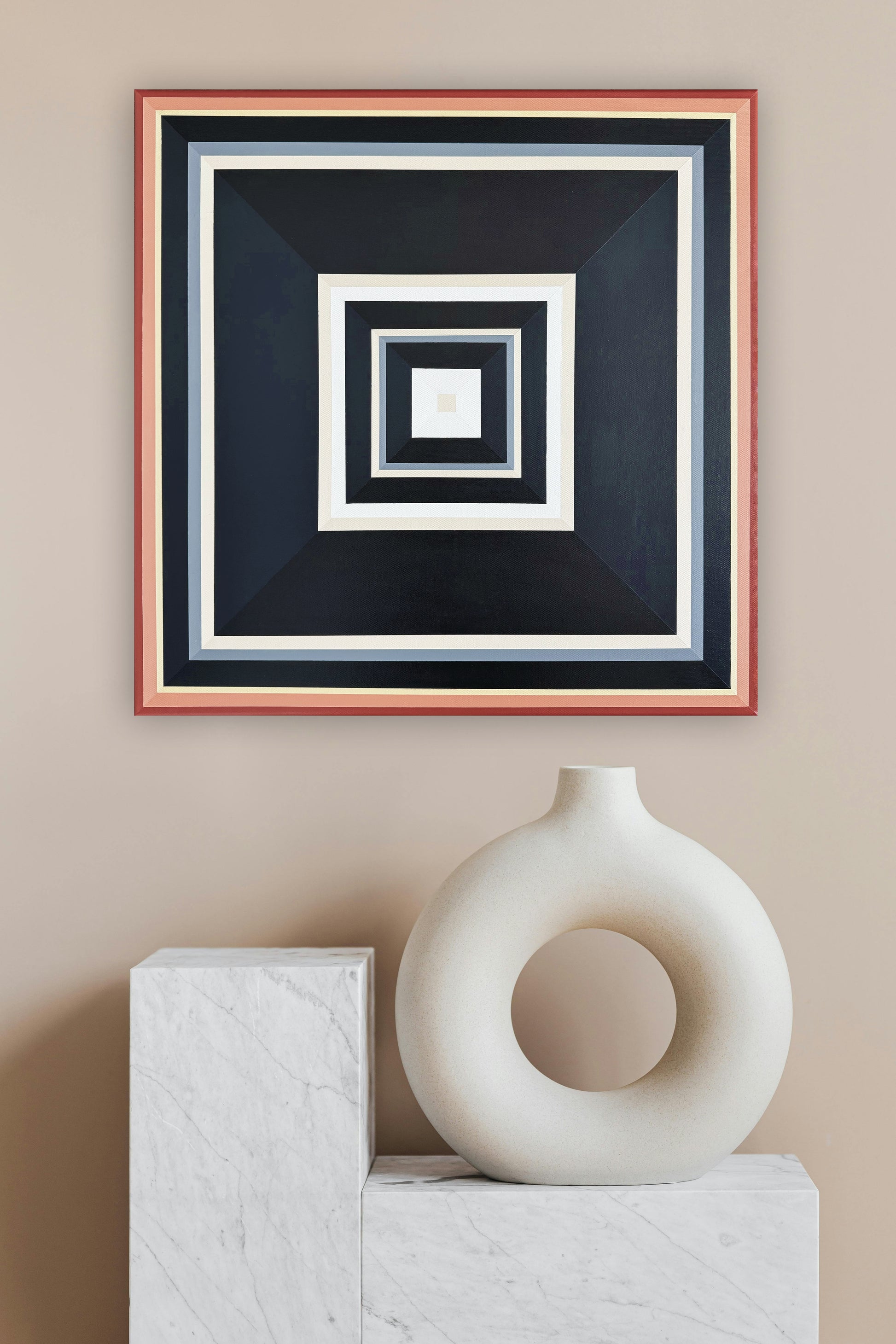 Black and Peach' by Elena Alexander - Hard edge abstract painting styled against warm greige walls with modern sculptural elements. The geometric composition features concentric squares in flat colors - from coral pink frame through dramatic black, cream, and dove grey to a crisp white center. This contemporary wall art demonstrates precise hard edge technique while harmonizing with a curated vignette of white ceramic vessel and marble blocks below. 