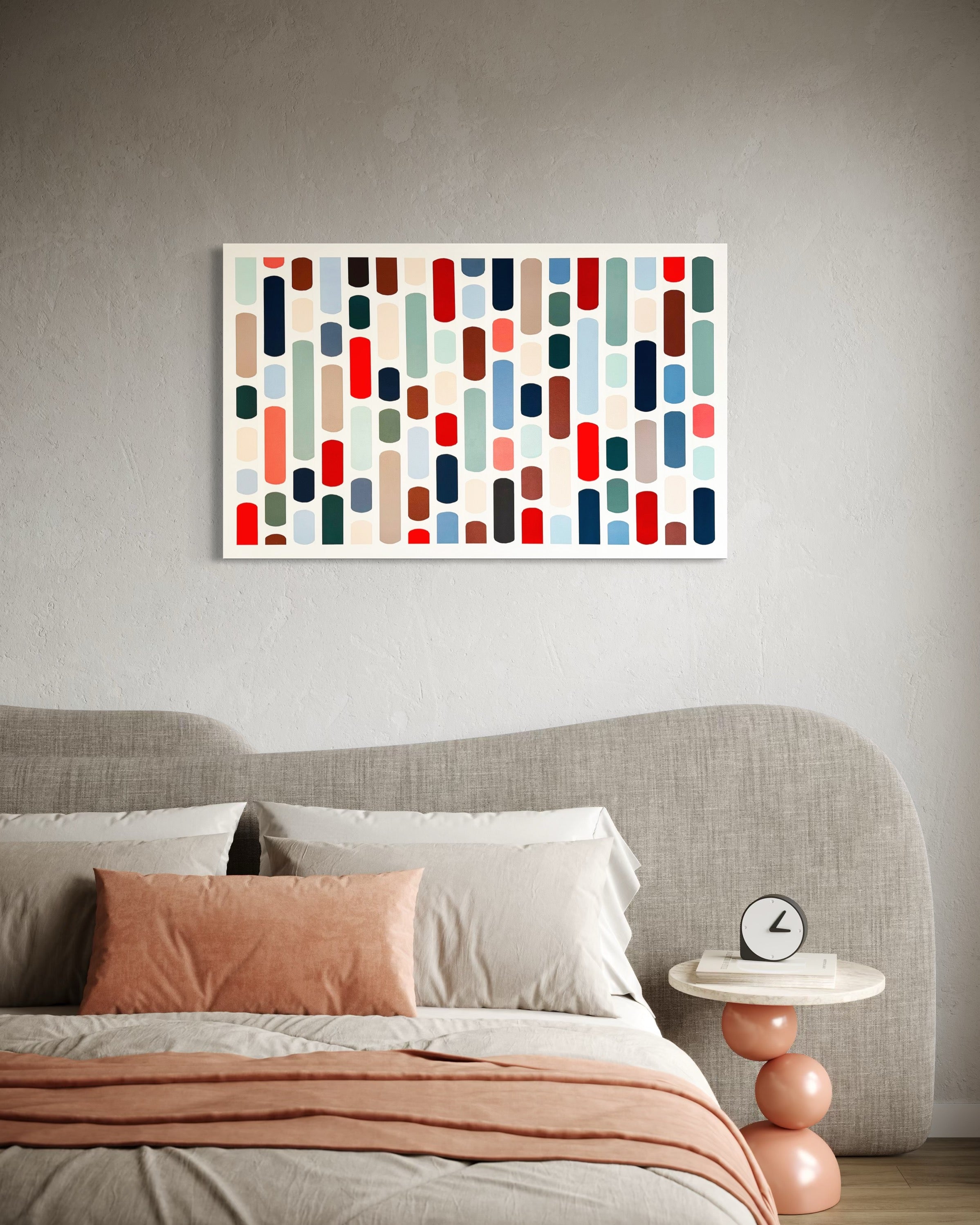 Abstract art print on a wall above a bed with a side table and clock.