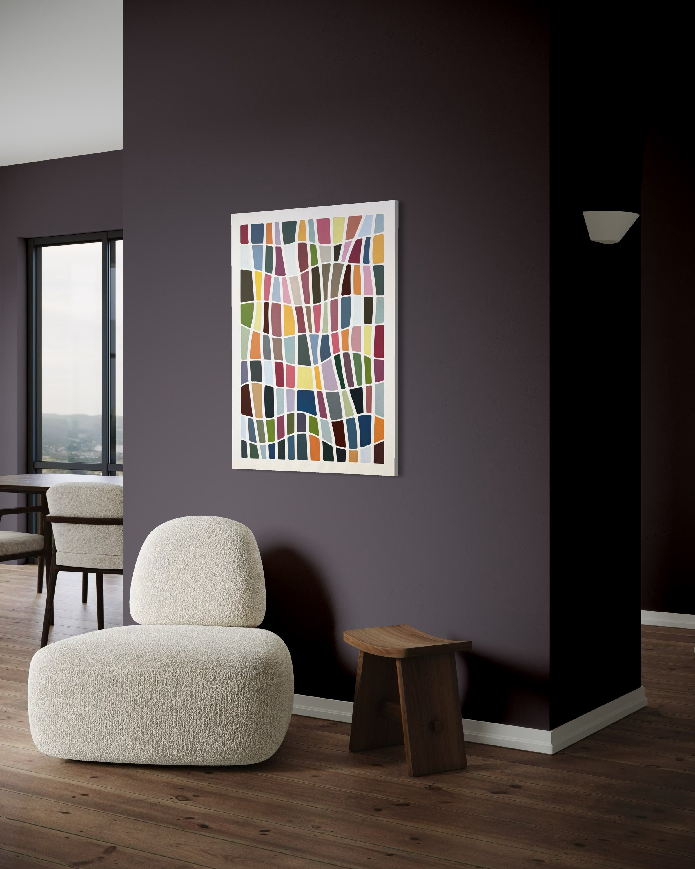 Modern interior with a white armchair, wooden stool, and colorful abstract art on a dark wall.