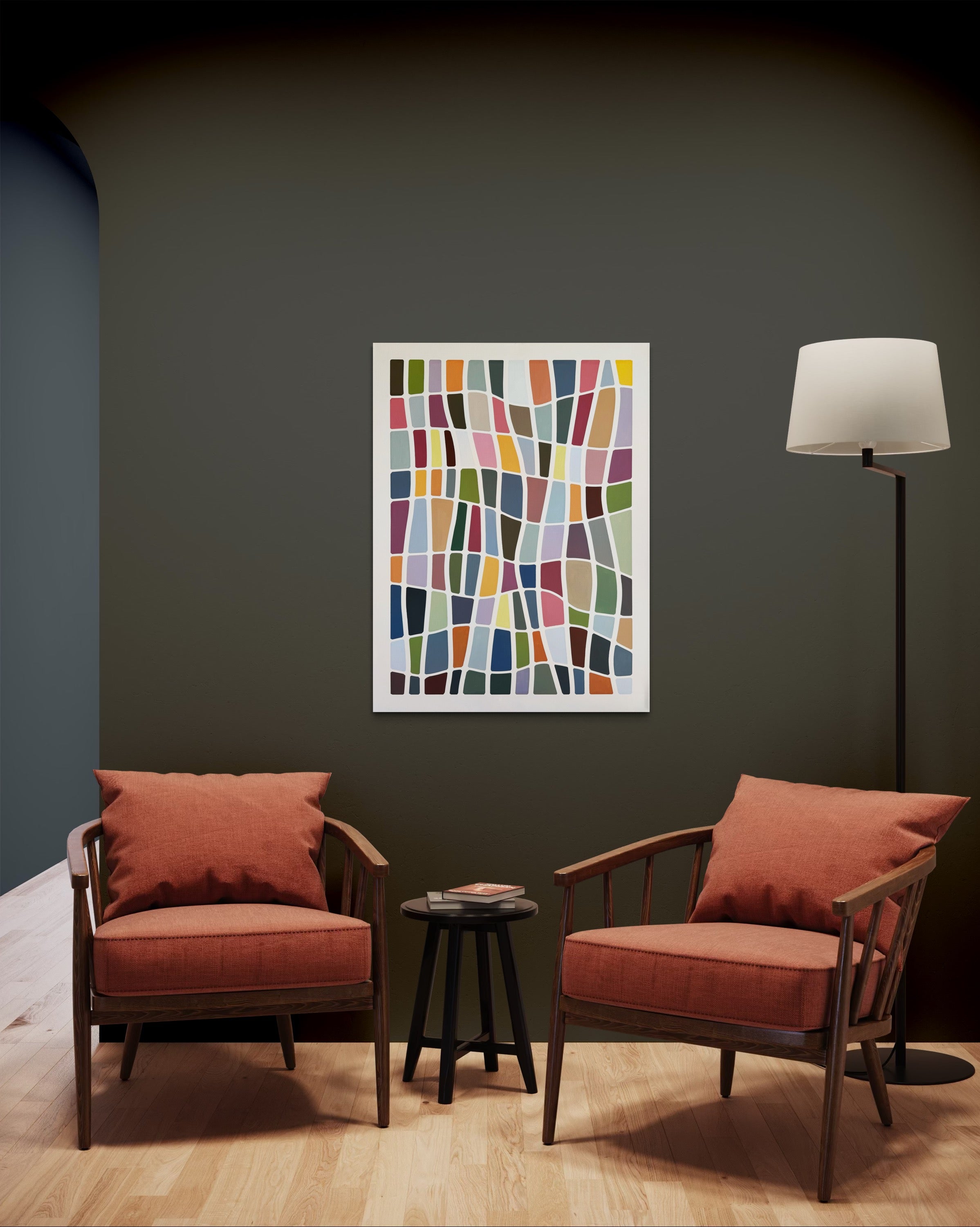 Two orange chairs with a small table and a colorful abstract painting on a dark wall.