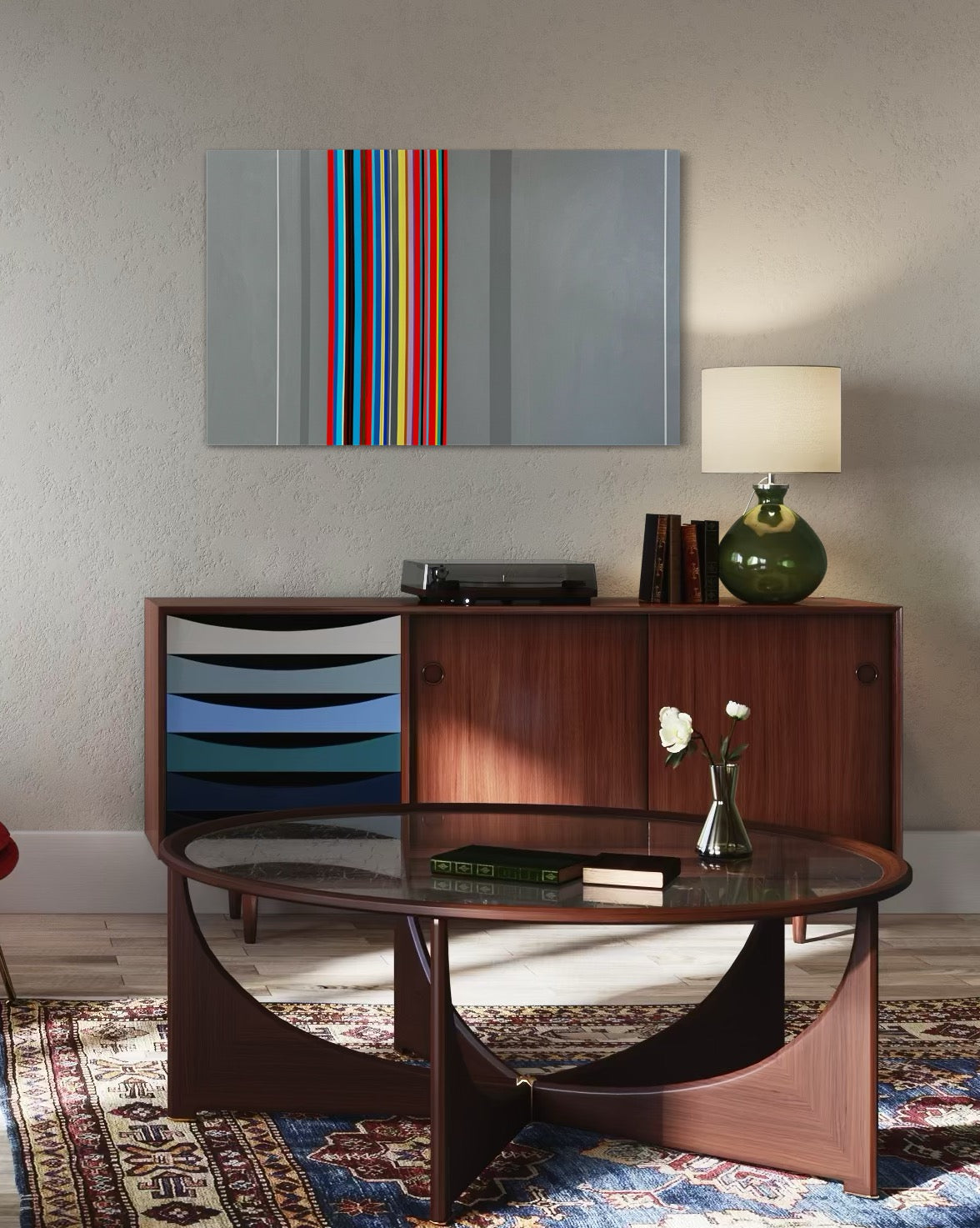 Wooden desk with a vase of flowers and lamp in a room with a colorful abstract painting on the wall.