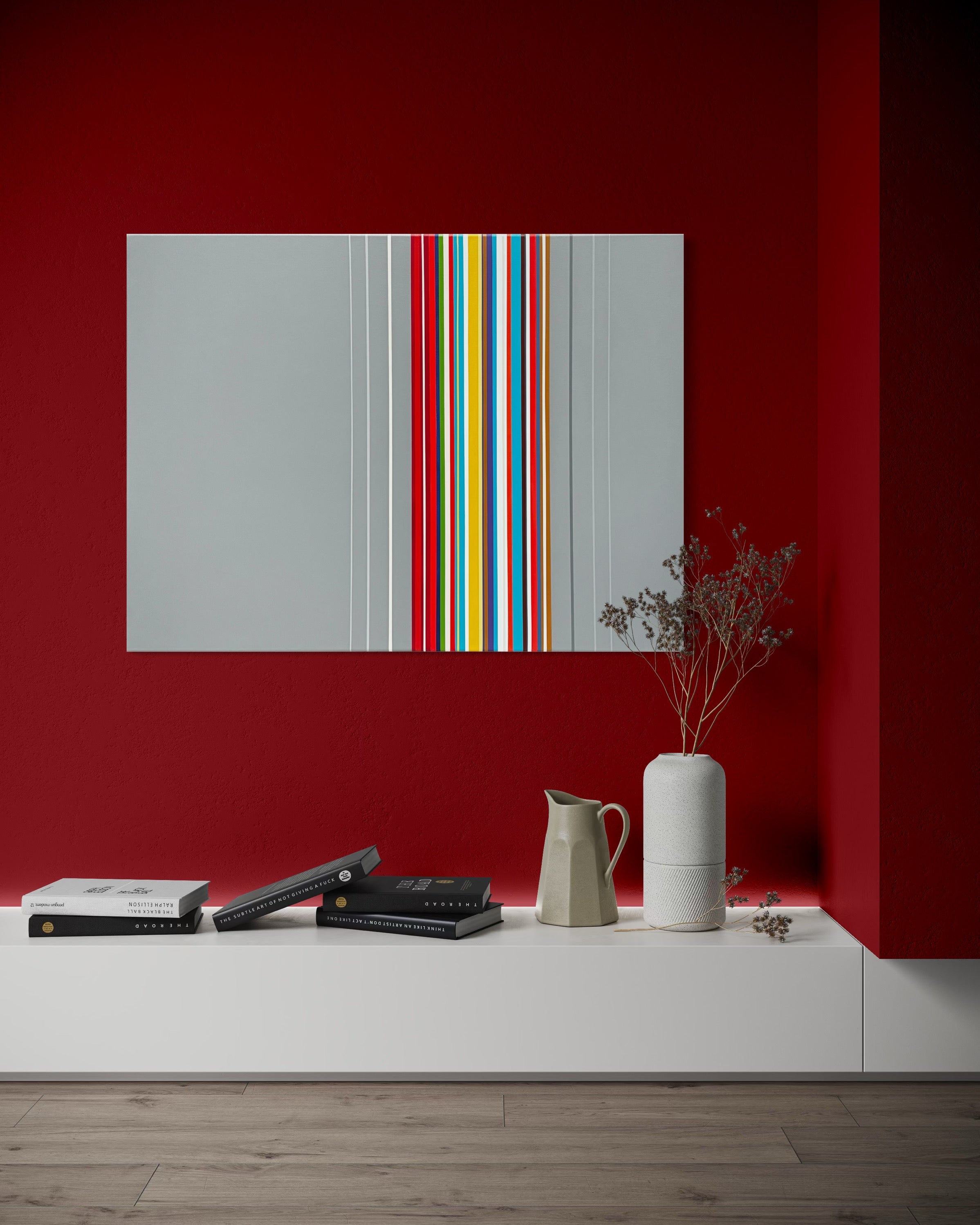 Modern interior with a colorful abstract painting on a red wall, books, and a vase.