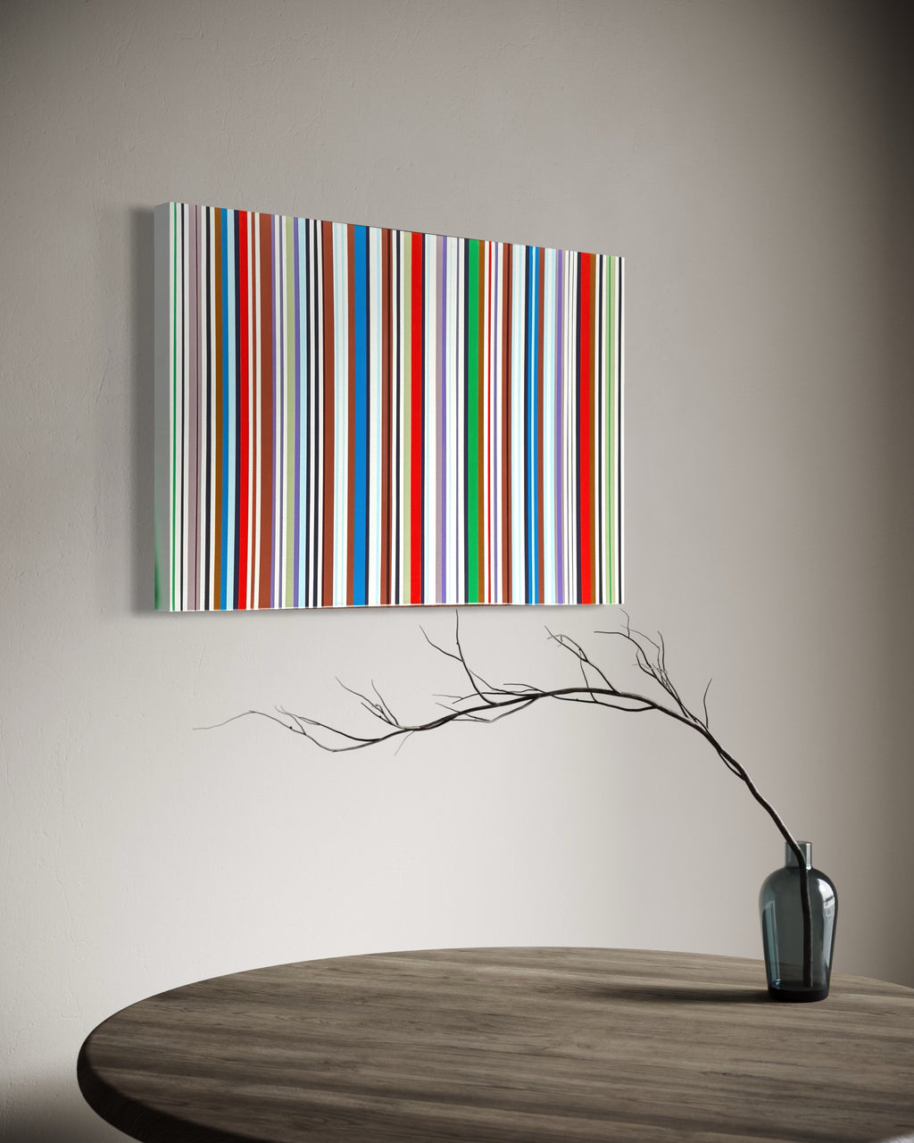 Colorful striped painting on a wall above a wooden table with a vase and branches.