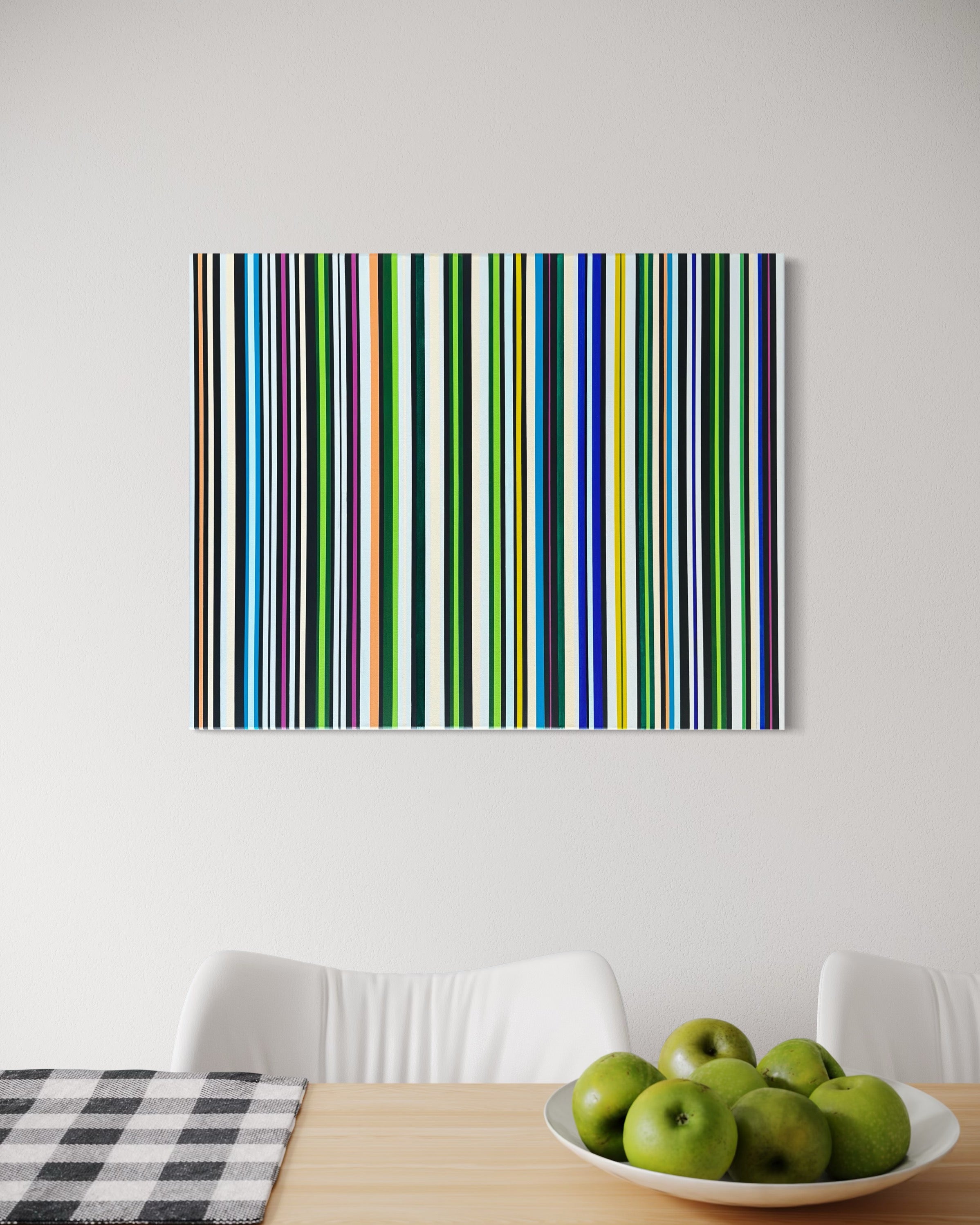 Colorful striped artwork on a white wall above a table with apples.