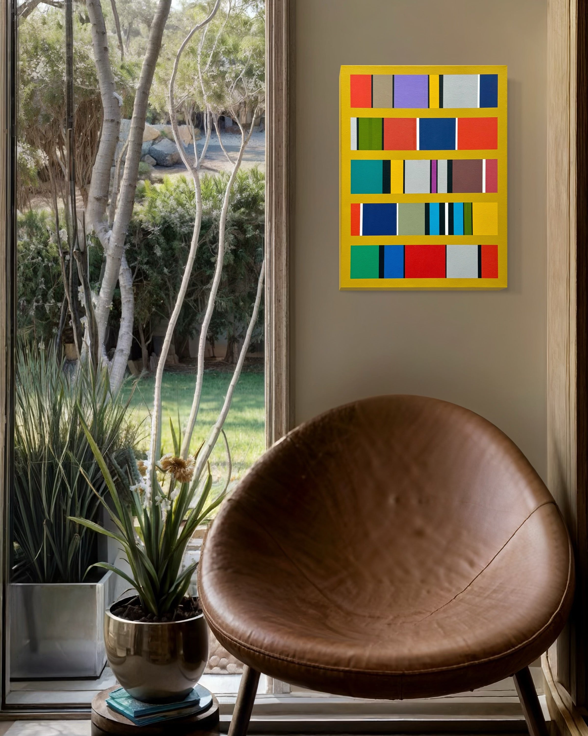 Colorful abstract wall art above a brown leather chair by a window with outdoor view