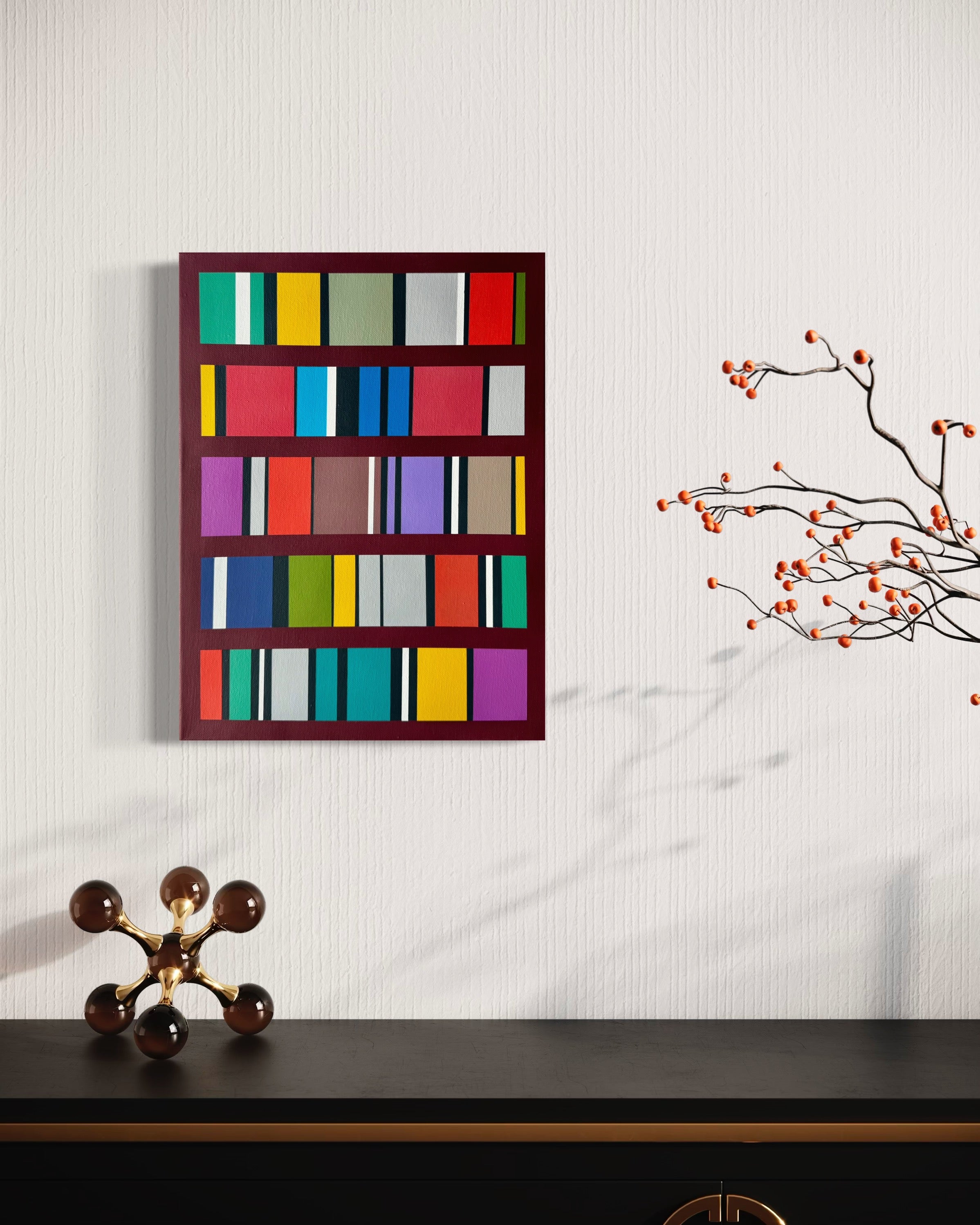 Colorful abstract art piece on a white wall with a decorative branch and sculpture below.