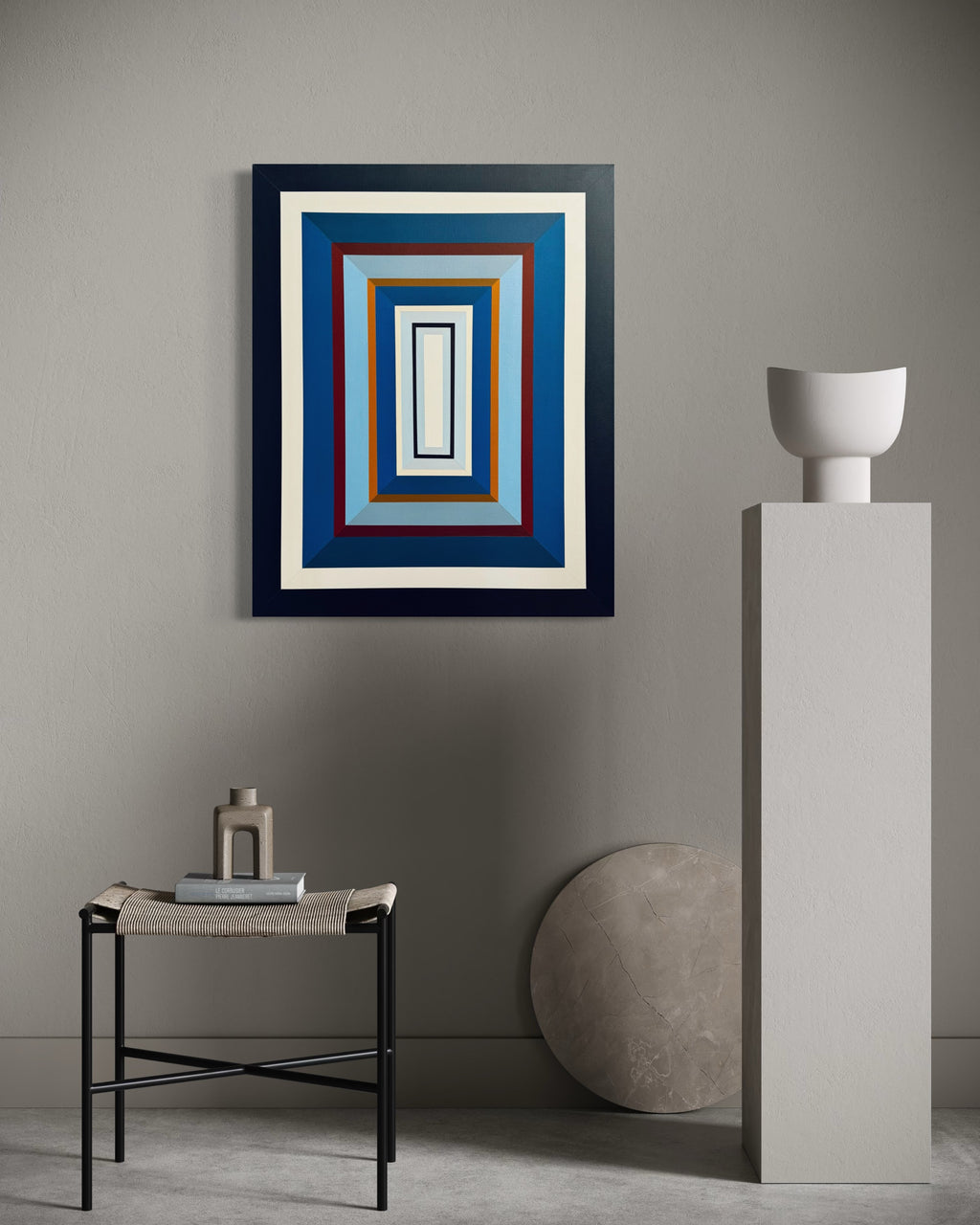 The "Denim-III" vertical painting adding a calming yet structured element to a minimalist space with a light grey wall and modern white ceramic vase.