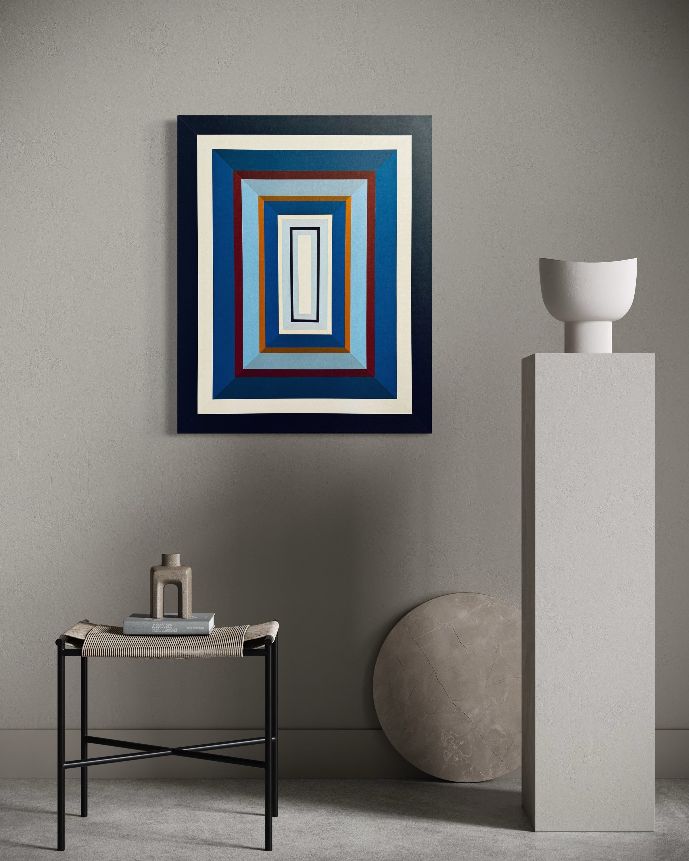 The "Denim-III" vertical painting adding a calming yet structured element to a minimalist space with a light grey wall and modern white ceramic vase.