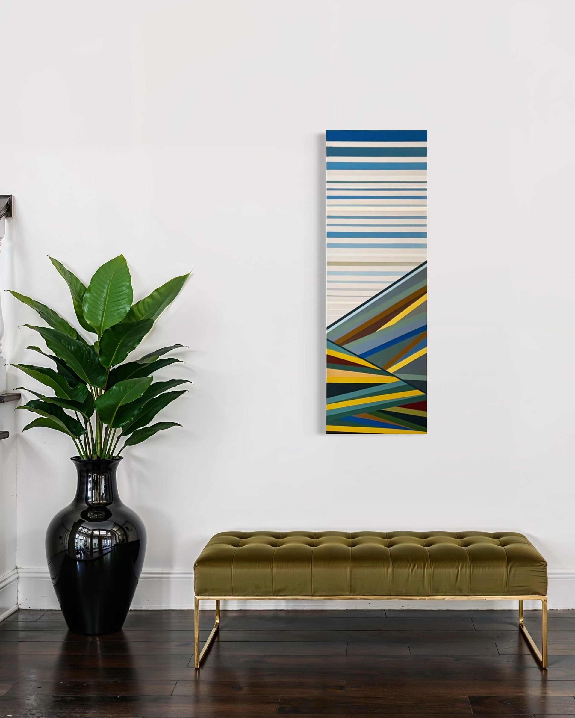 The tall, narrow "Foothills" painting creating a striking vertical element in a modern entryway, with its green hues complementing the upholstered bench below.