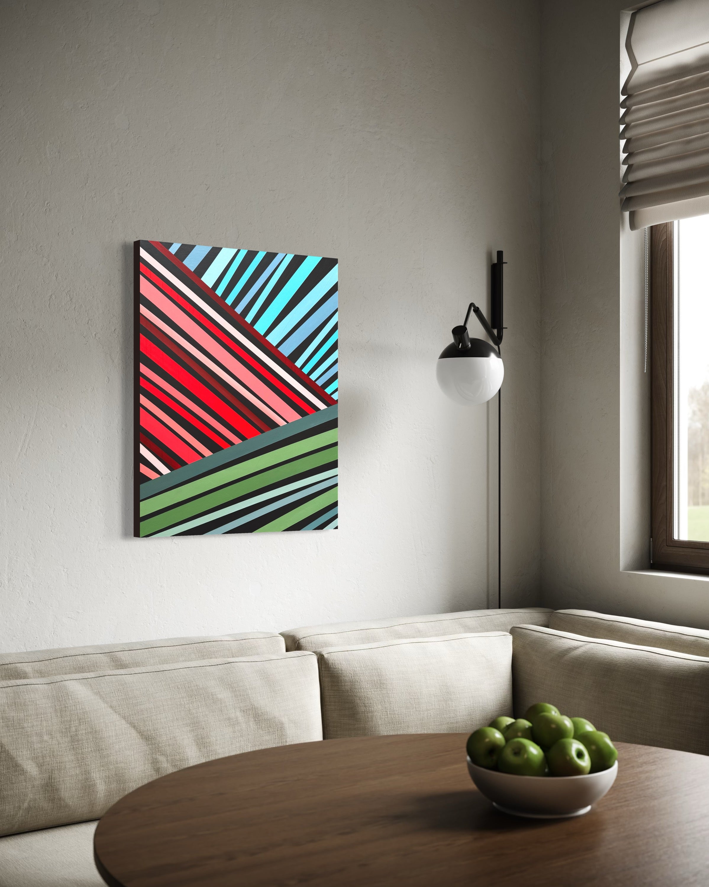 Abstract art piece on a wall above a sofa with a bowl of apples on a table.