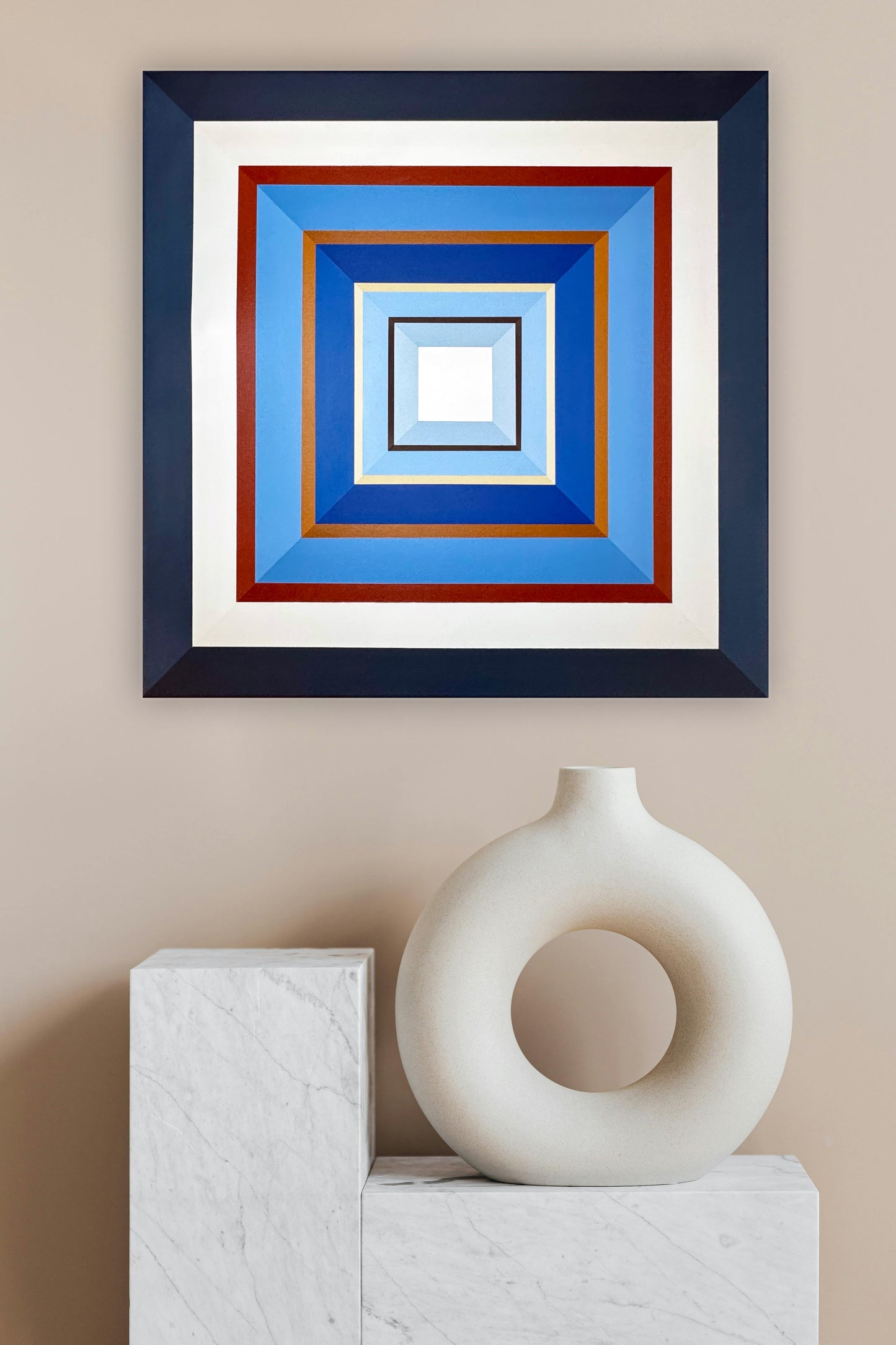 Hard edge abstract painting by Elena Alexander, featuring concentric squares in navy, white, rust red, and blues. Styled above modern marble blocks and white ceramic vessel, the geometric wall art creates striking contrast through flat color precision and clean lines. Contemporary minimalist piece showcasing hard edge painting technique.